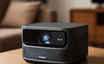 Alt-Text: „Kompakter JMGO N3K Triple-Laser-Heimkino-Projektor auf einem Wohnzimmertisch, projiziert ein großes, helles 4K-Bild an die Wand; beworben mit integriertem Google TV und einem Preis von 1.199 Euro.“