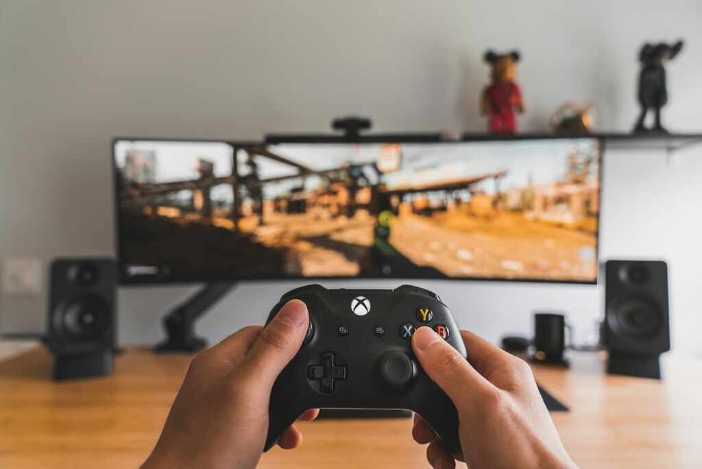 Person mit Gamecontroller als Symbol für PC- und Konsolenspiele