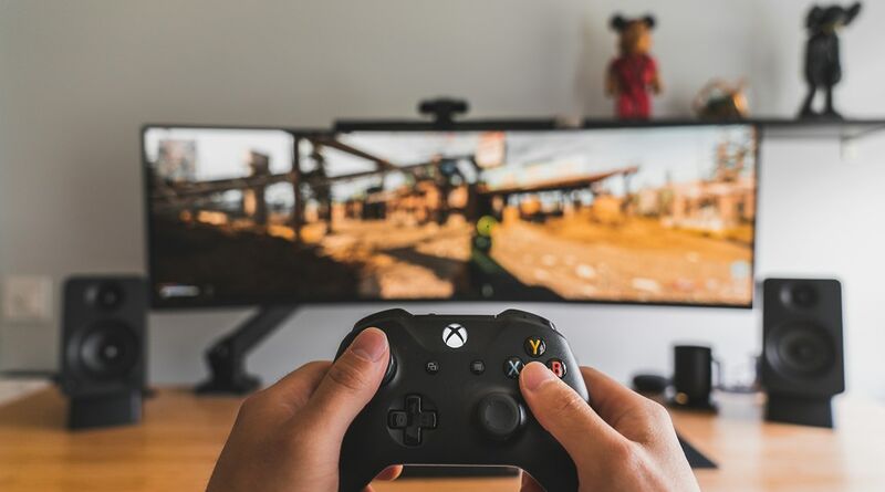 Person mit Gamecontroller als Symbol für PC- und Konsolenspiele