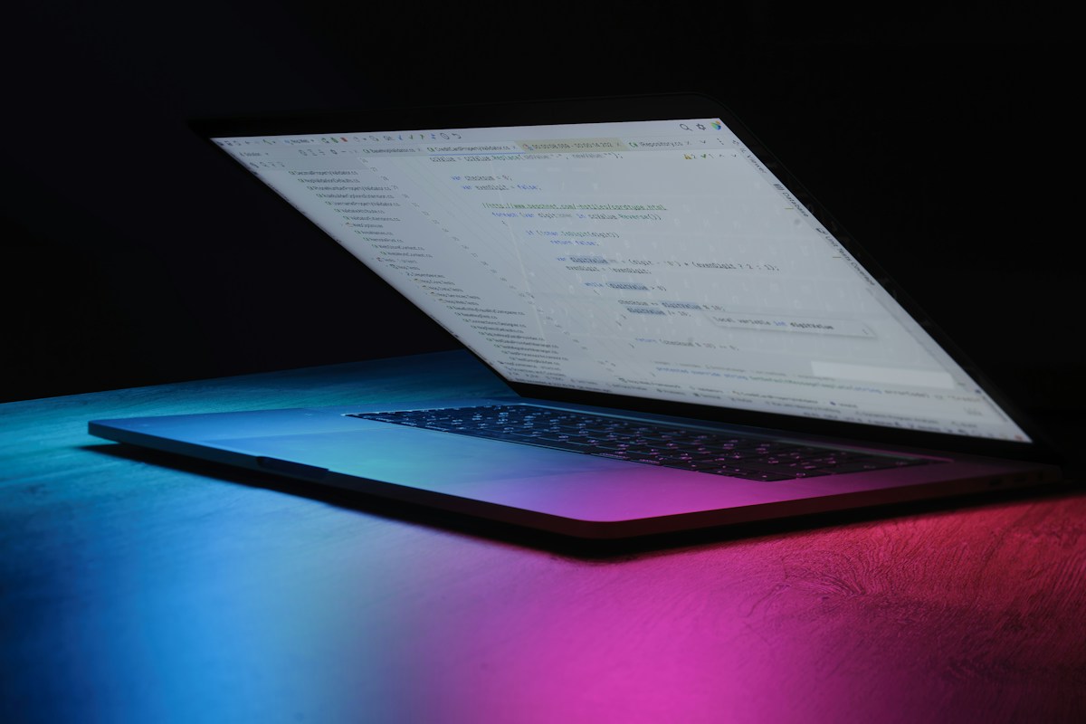 Laptop mit Programmcode bei Neonbeleuchtung, Symbolbild für Git-Infrastruktur