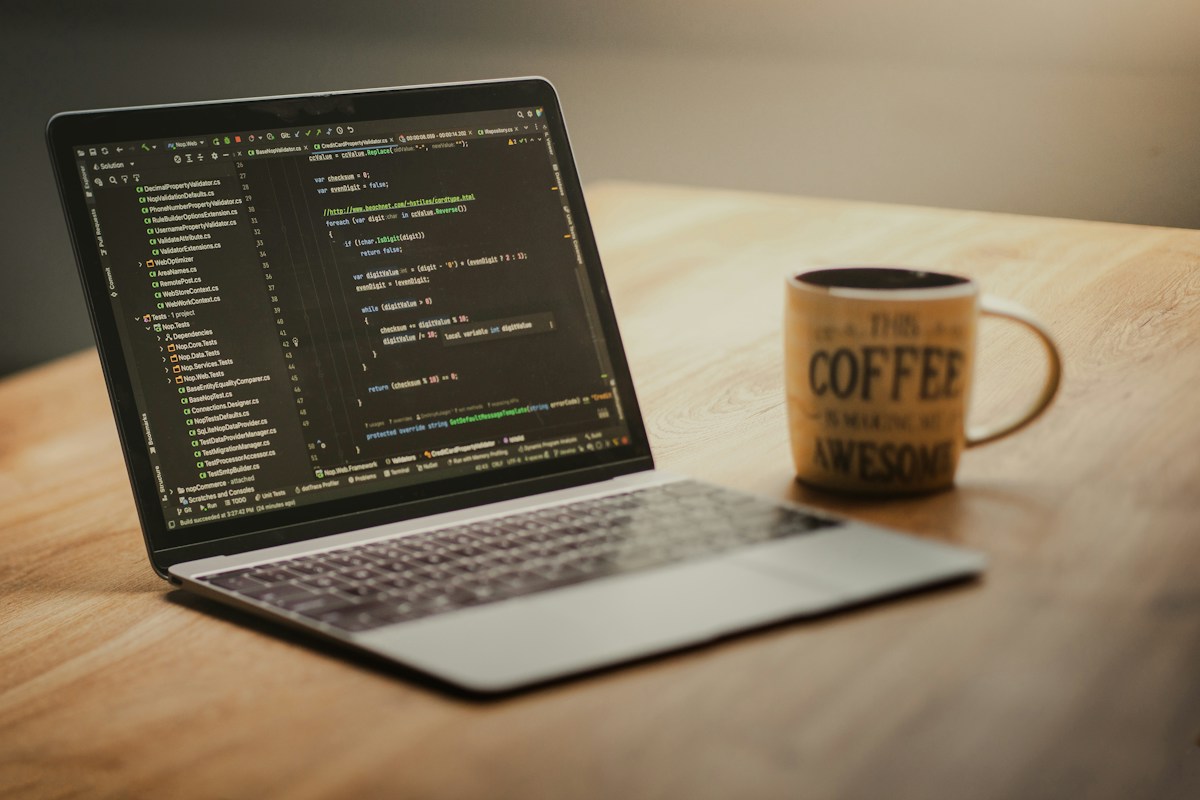 Laptop mit Code und Tasse auf dem Tisch, Symbolbild für IT-Auswertung