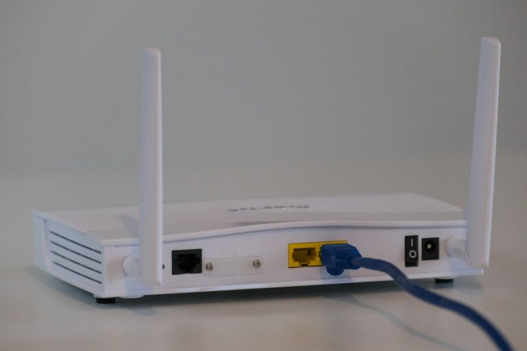 Rückseite eines weißen WLAN-Routers mit Antennen und eingestecktem Netzwerkkabel