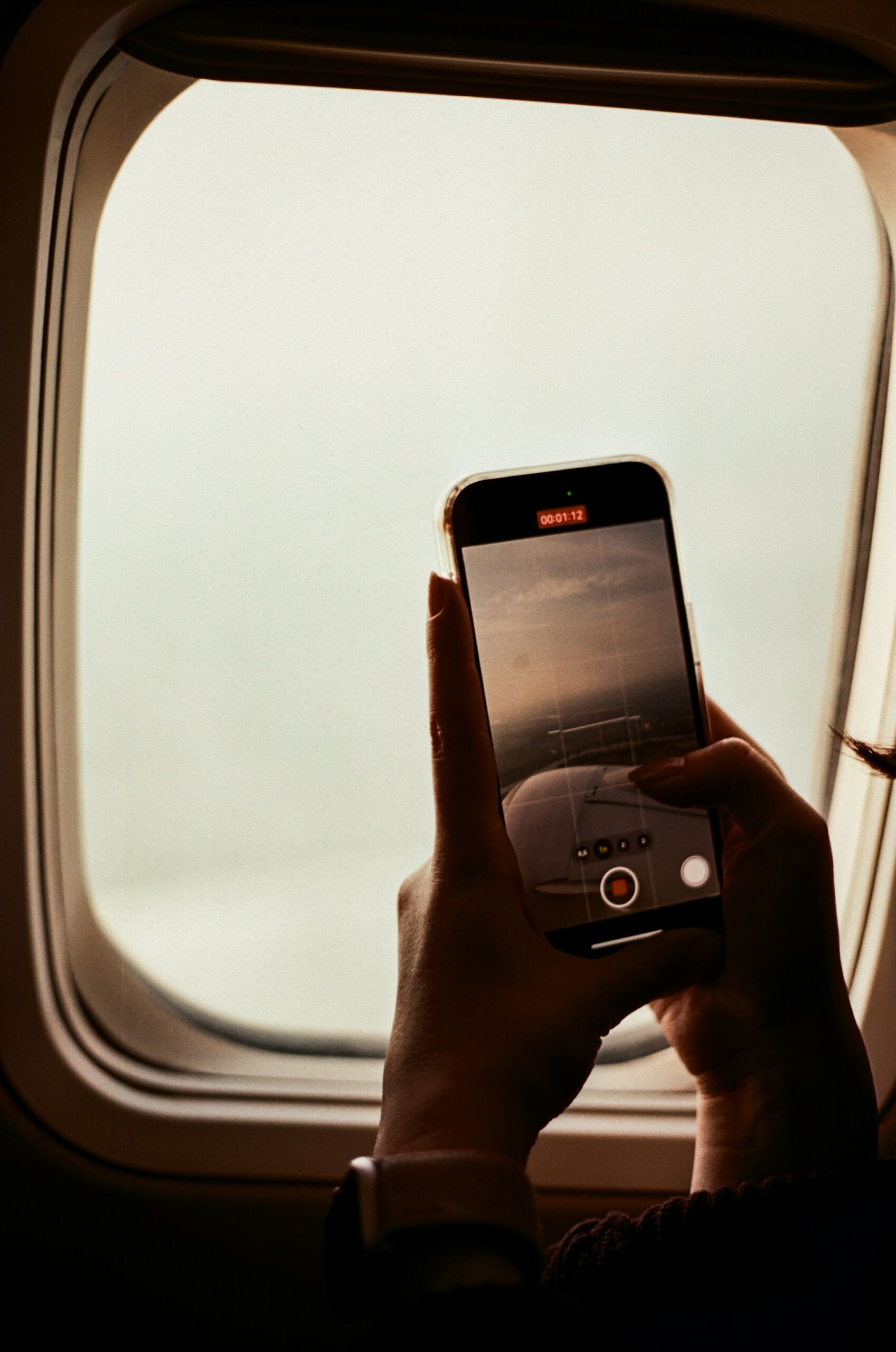Smartphone vor einem Flugzeugfenster – mobiles Internet per eSIM ist besonders für Reisen interessant