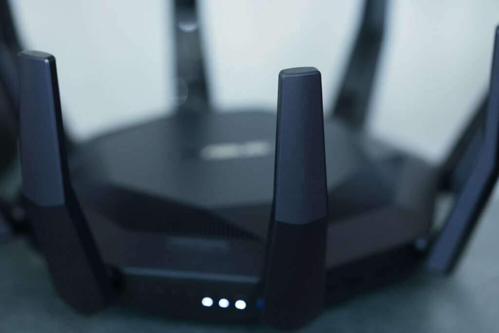 Nahaufnahme eines schwarzen WLAN-Routers mit mehreren Antennen und leuchtenden Statusanzeigen